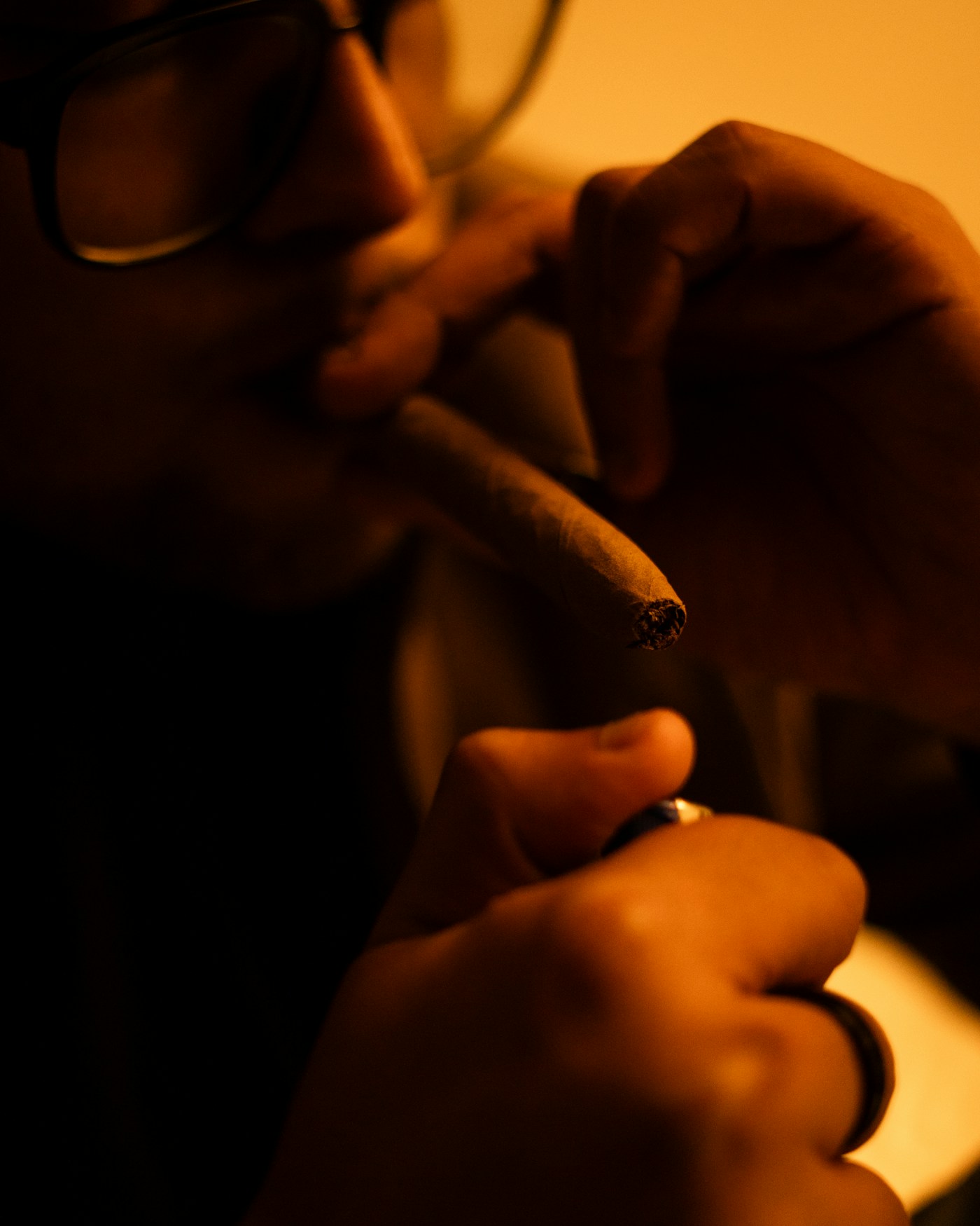 Dark luxury cigar lounge detail with warm smoke and craftsmanship mood